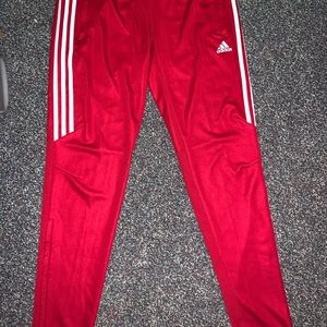 Red adidas sweatpants with three white stripes.